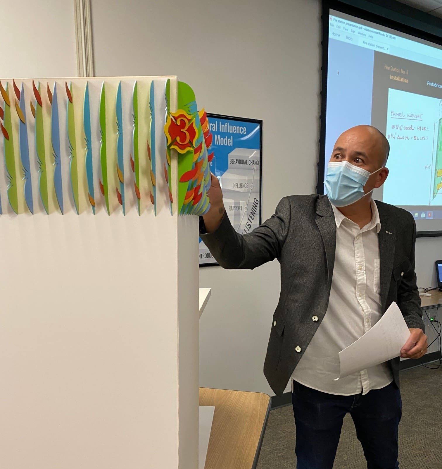 Artist standing next to art maquette describing the art.