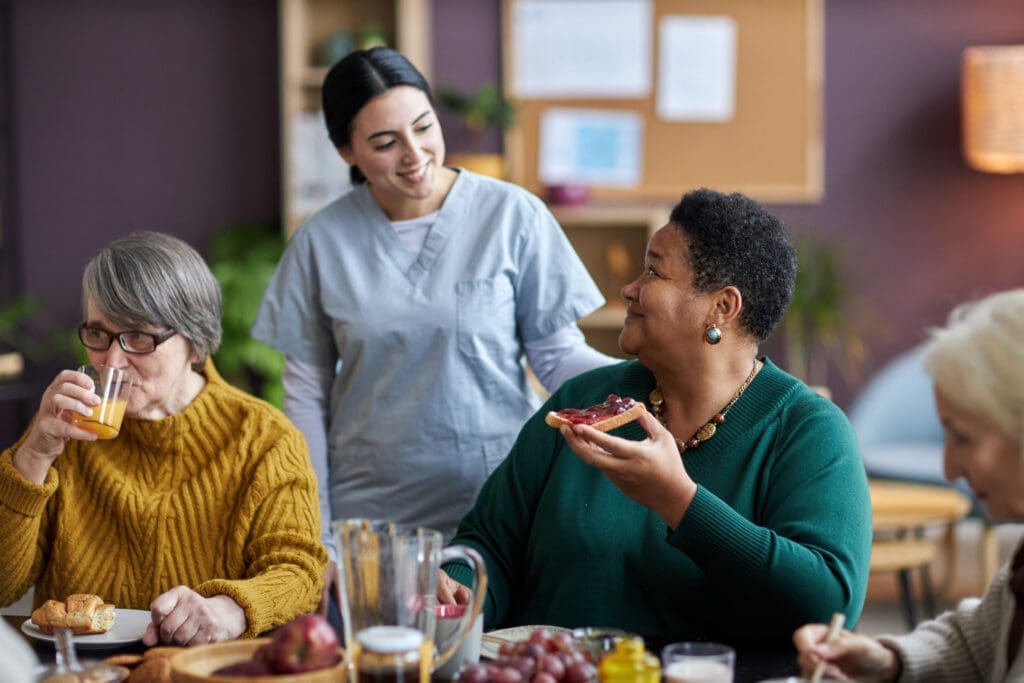 Nurse assisting senior people during breakfast.