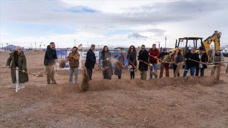 Group of people shoveling dirt at a groundbreaking ceremony
