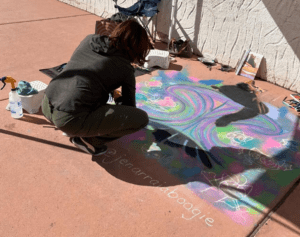 Woman kneeling near chalk art on pavement