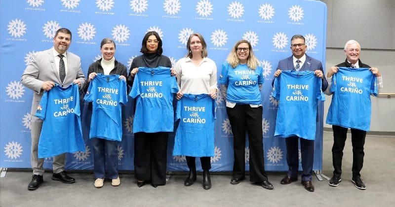 LCPS Superintendent. City Council members, and Mayor holding up Thrive with Cariño shirts.