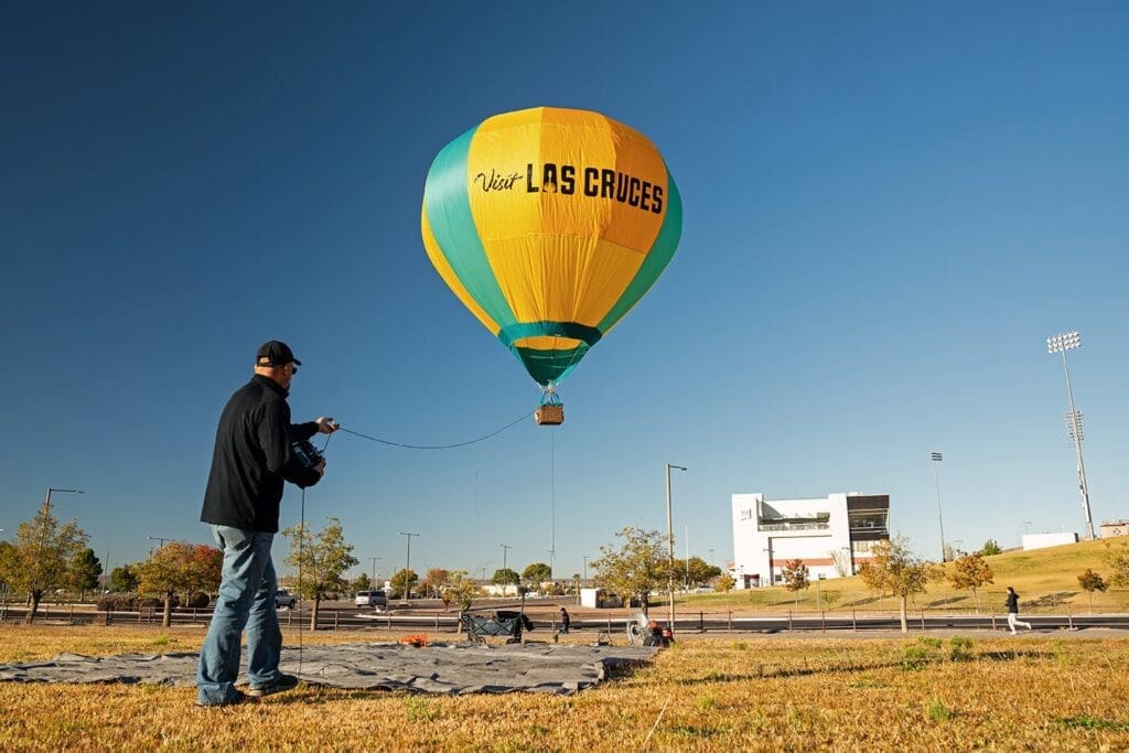Man standing in front of hot air balloon that is in the air.