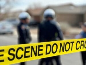 A photo of a two police officers and a yellow tape stating do not cross