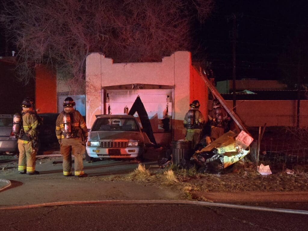 Two firefighters standing in front of a house.