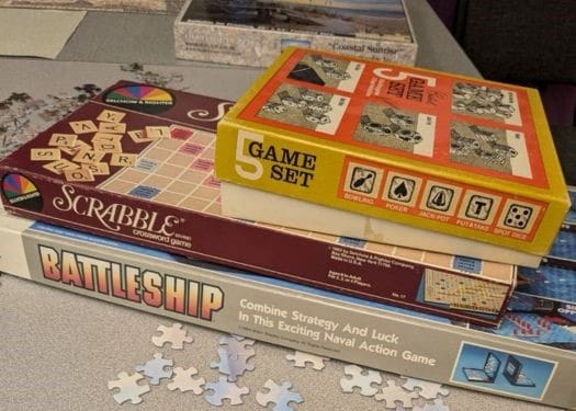 Three board games stacked on top of each other on a table.