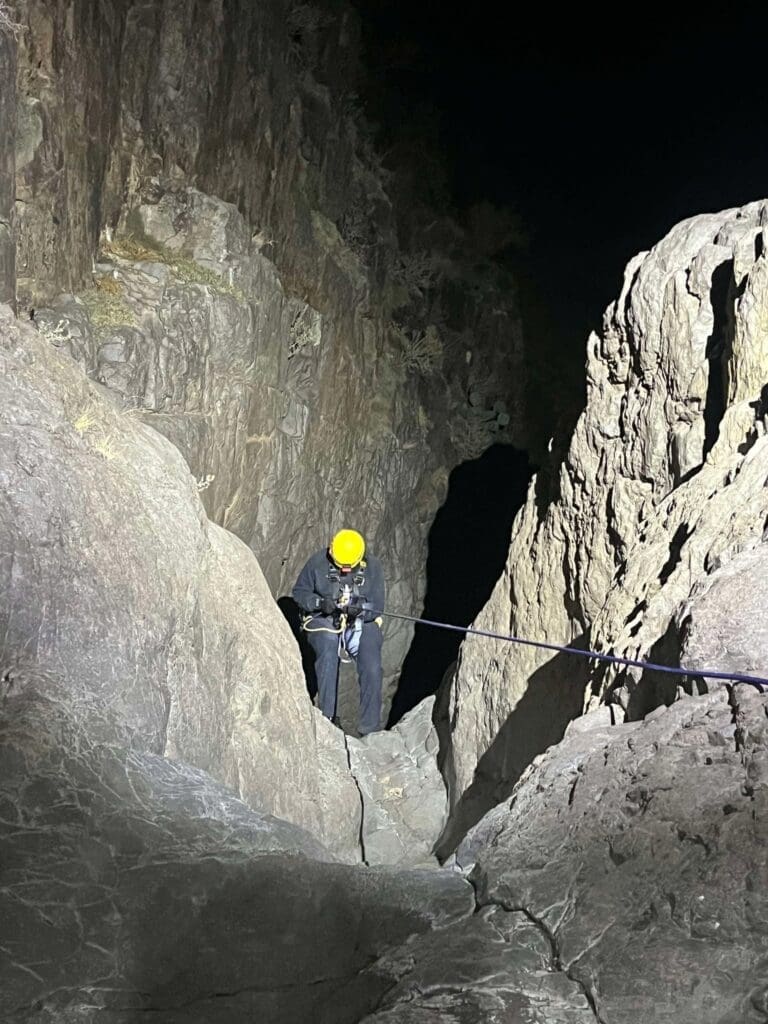 Rescuer in climbing gear climbing down a mountain.