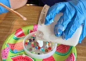 Photo of someone pouring paint on a plate and a brush