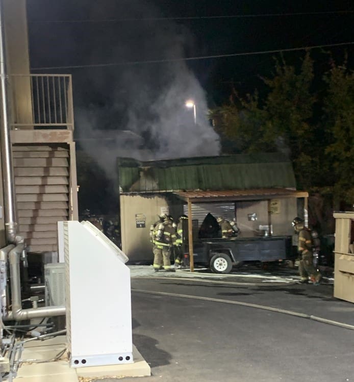 Firefighters working to put out a fire in a shed behind a building.