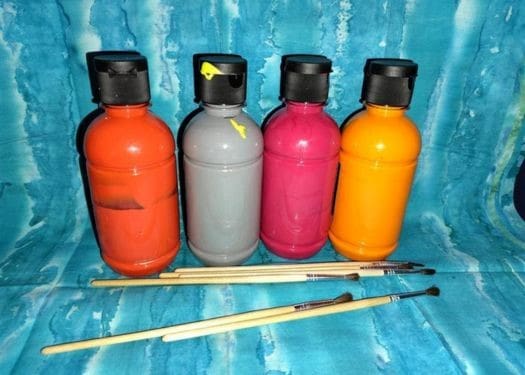 Bottles of paint and some paint brushes.