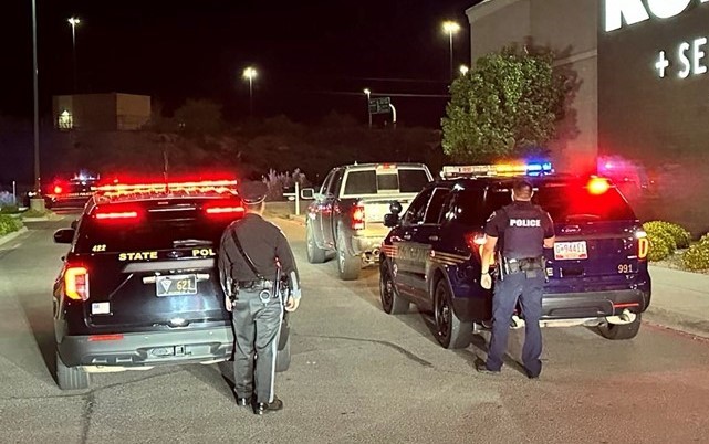 Two police cars stopped in a parking lot with their lights on.