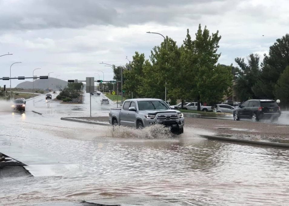 Truck driving through running water in a street.