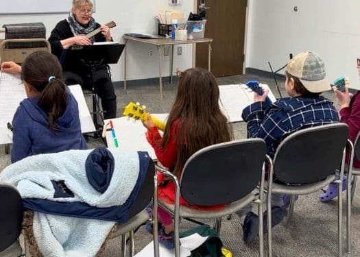 Teacher with ukulele teaching students how to play.