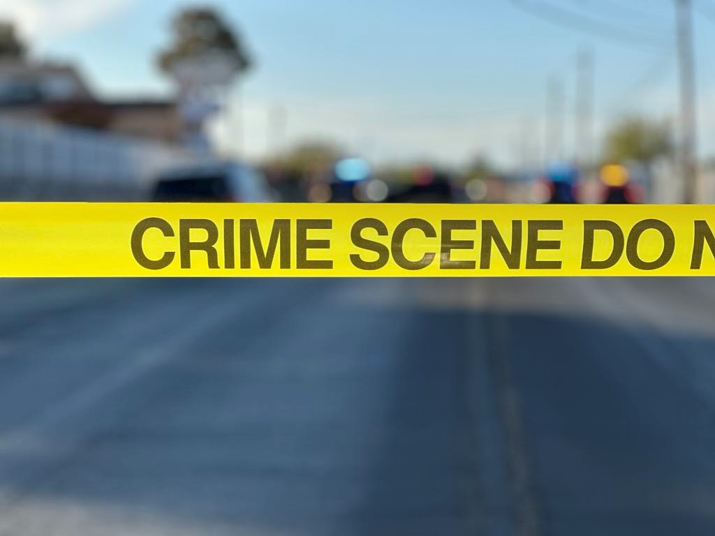Crime scene tape in front of a road.