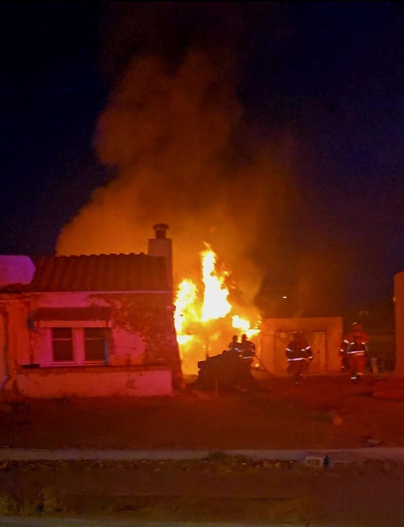 Firemen fighting a house fire at night.