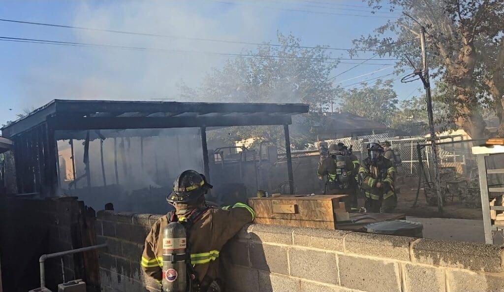 Firefighters examining damage to a shed.