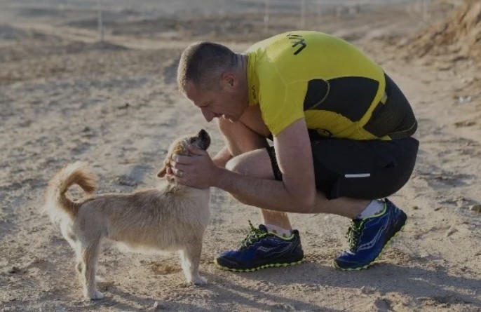 Man hugging dog in the desert.