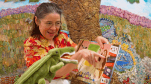 Lady reading a book to an alligator puppet.