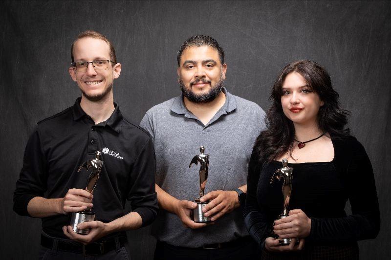 Three people holding trophies.