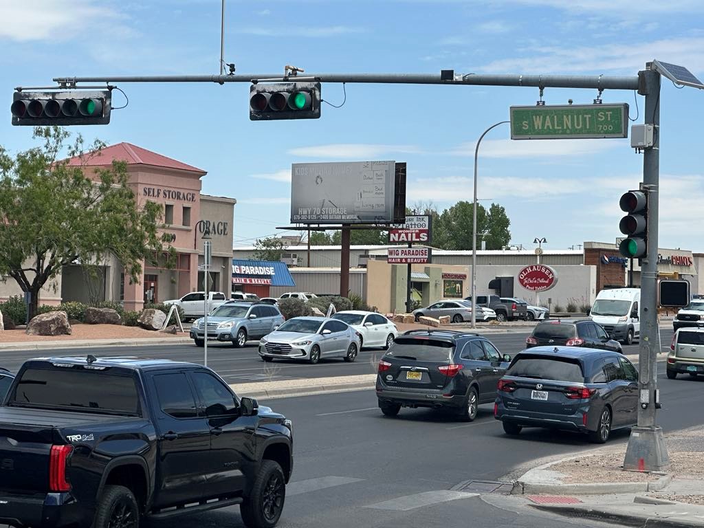 Traffic light at an intersection with cars driving by.