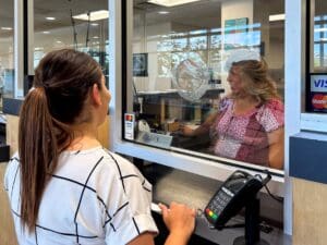A cashier assisting a customer at the cashier's window.