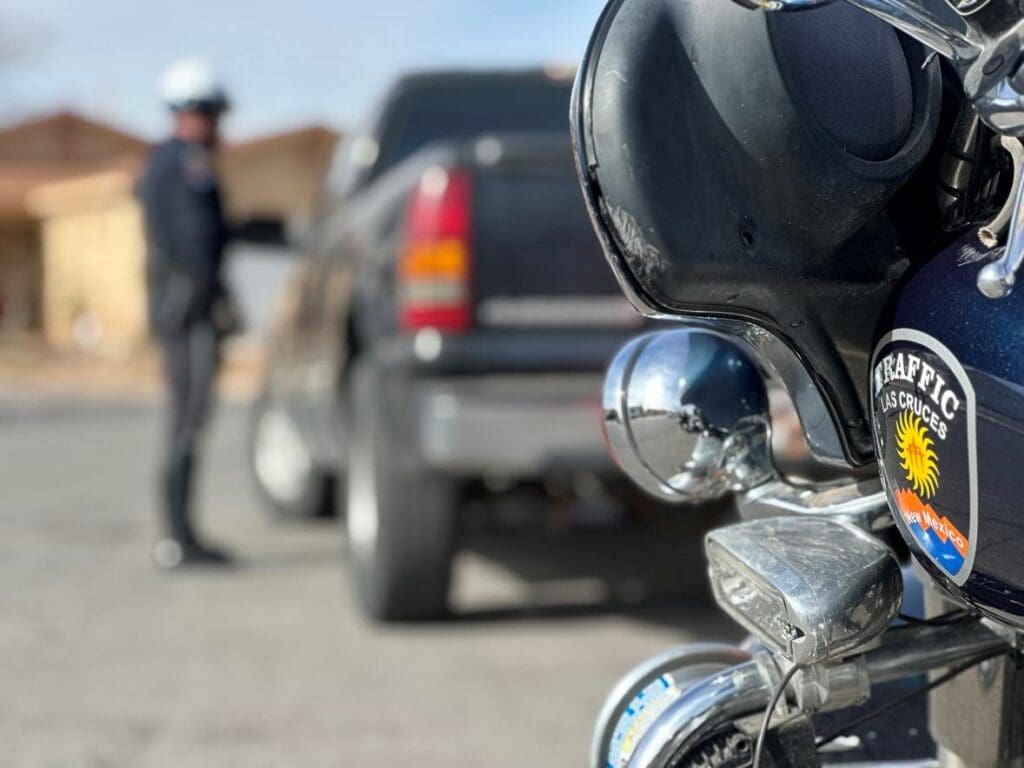 Front of a motorcycle parked behind a truck and an officer talking to the driver of the truck.