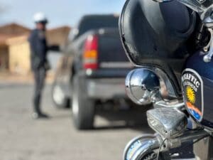 Front of a motorcycle parked behind a truck and an officer talking to the driver of the truck.