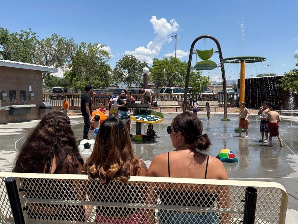 Three girls sitting on a bench at the splash pad.