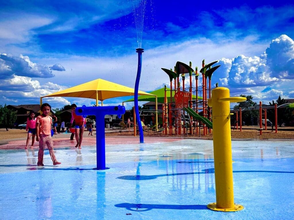 Children playing in a splash pad at a park.