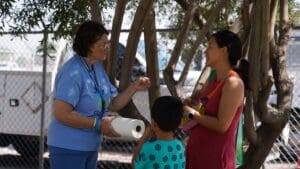 People talking in the shade under a tree.