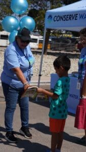 Woman pointing to a booklet held by a child by a pop-up tent.