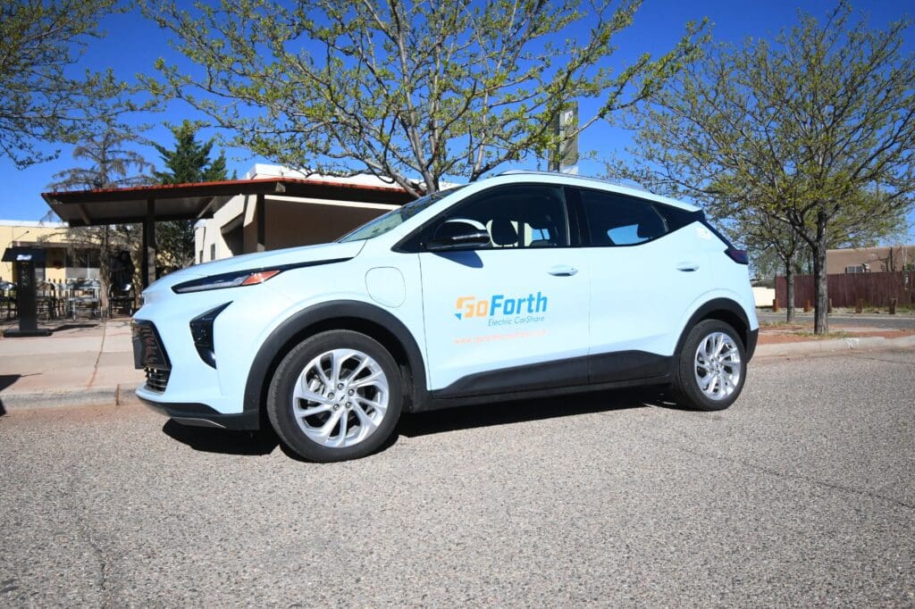 An electric vehicle parked in front of a house.