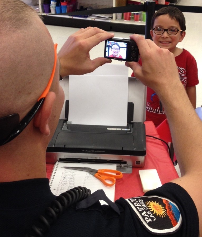 Police officer taking a picture of a child.