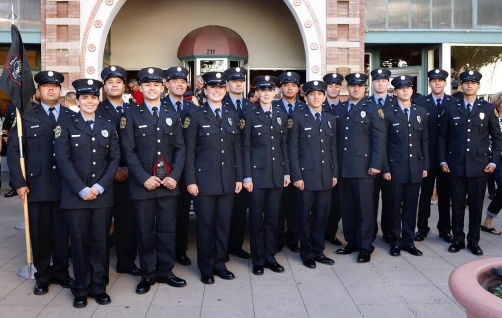 Las Cruces Fire Department's 38th Academy's 16 new firefighters standing in front of a building.