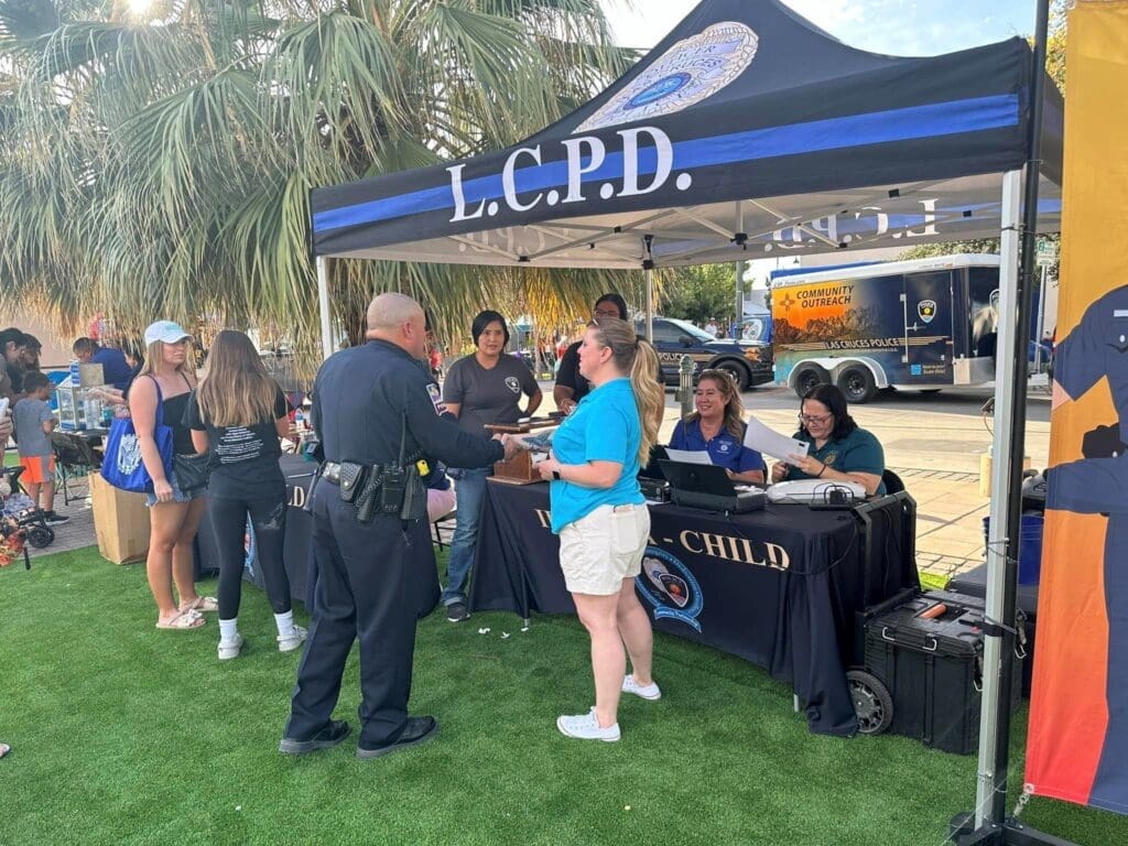 Police officer talking to a lady at the LCPD canopy set up outside in the grass.