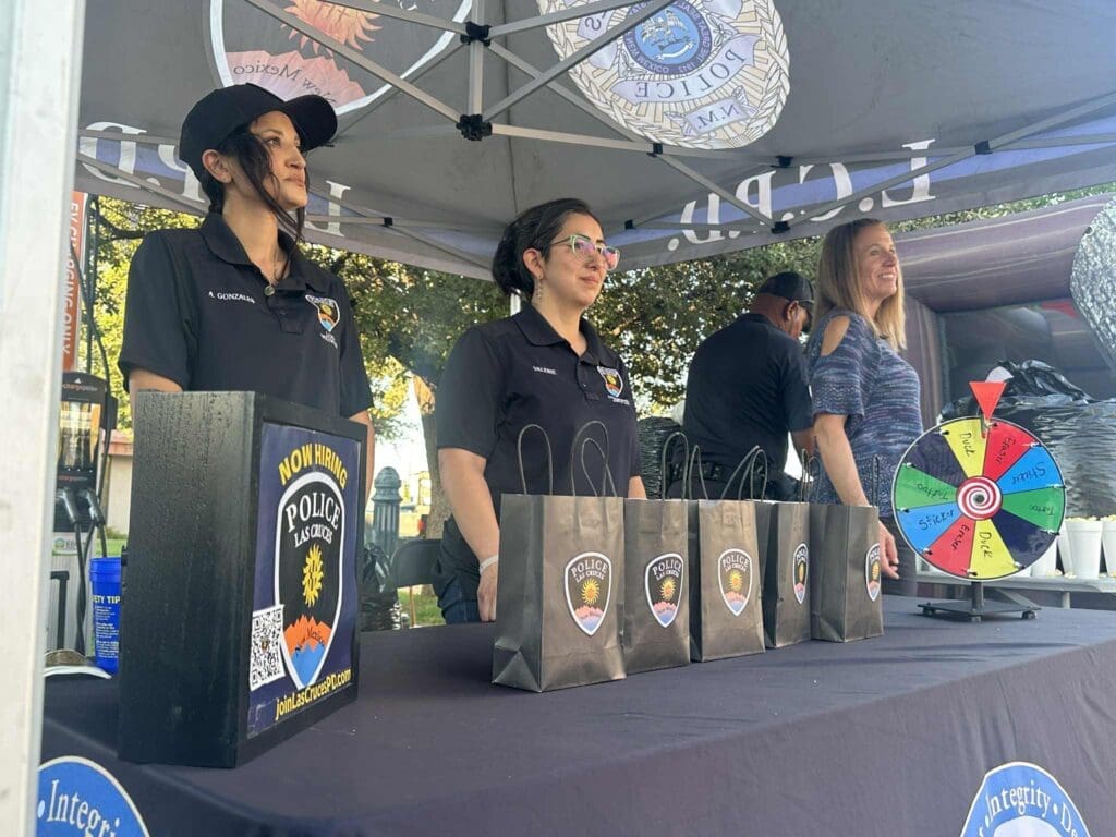 Three ladies standing behind a table at an outdoor event.