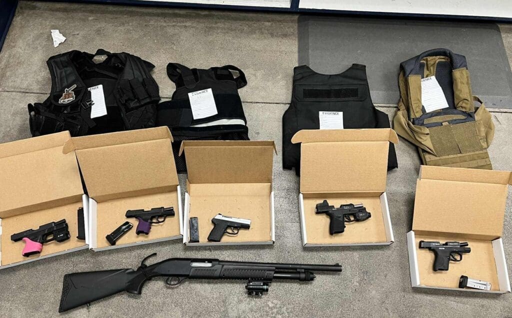 Guns in a box on the floor with bulletproof vests.