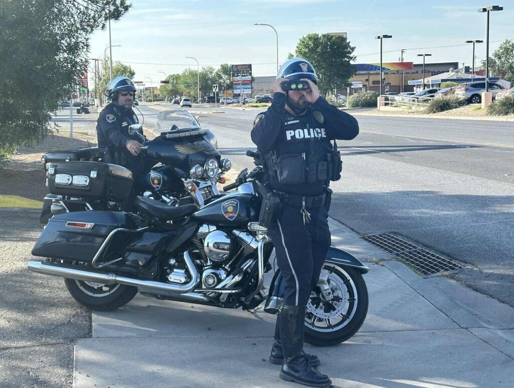 Two police officers on motorcycles parked on the side of the road.