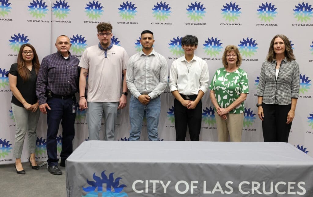 Group of people standing in front of a table.