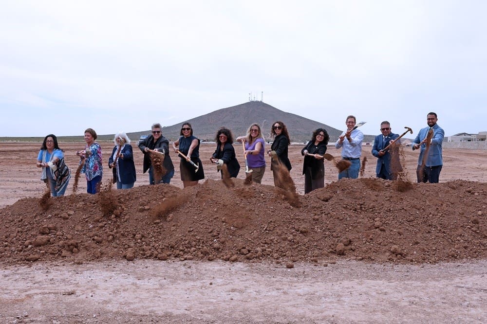 People standing in a line shoveling dirt.