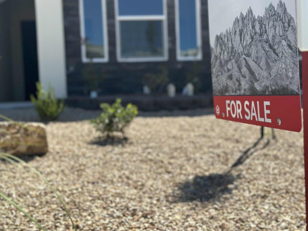 For sale sign in a yard in front of a house.