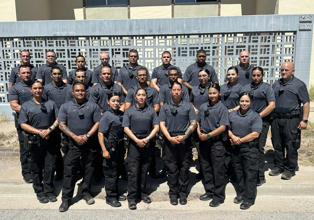 Group of Las Cruces Police Department cadets standing in front of a decorative wall.