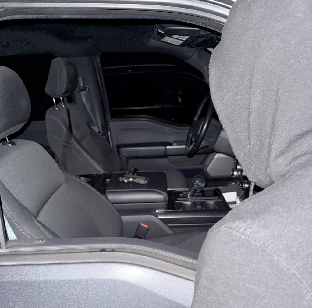 Person in a hoodie looking into a vehicle.