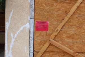 Red tag on boarded up building that says "No Trespassing Condemned."