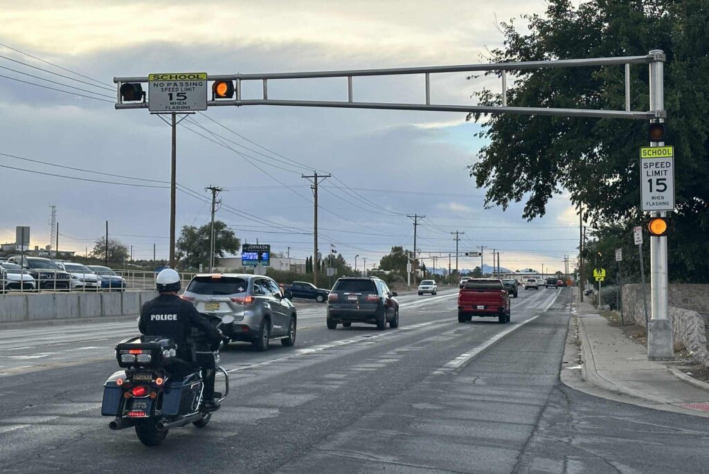 Motorcycle officer driving through a school crossing zone.