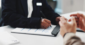 Checklist being filled out by intake person while hands of perceived patient are in foreground.
