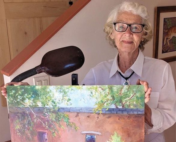 Carolyn Bunch standing behind one of her paintings.