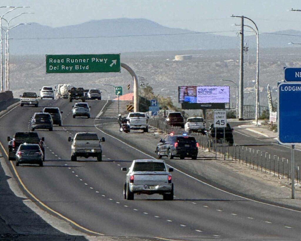 Cars driving on a highway with mountains in the background.