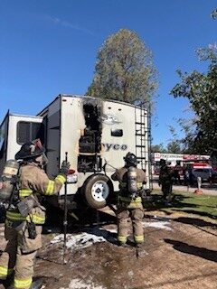 Firefighters inspecting fire damage to camper.