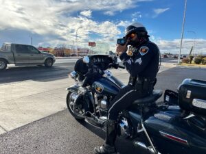 Officer on a motorcycle parked in a parking lot with a radar gun.
