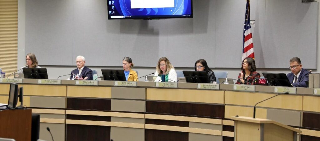 Six city councilors and mayor sitting behind a desk.